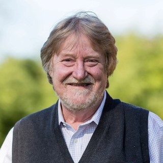 Kurt Johnson, a white man with reddish-blond hair, wearing a light blue button up shirt with a dark blue V-neck vest.