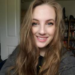 Fiona Dolezal a white woman in her twenties with long hair smiling in her home office.
